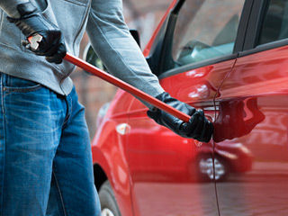 photo: A person brandishing a crowbar is breaking into an automobile